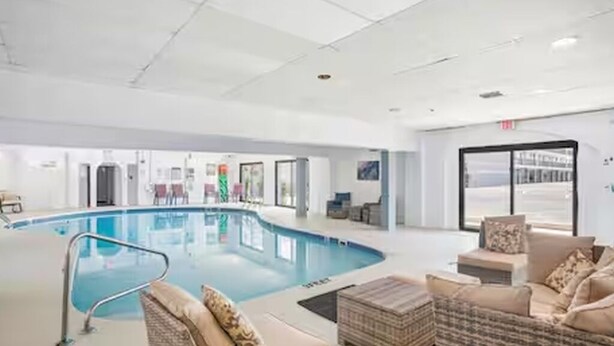 Piscina interna com espreguiçadeiras e teto transparente.