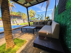 An outdoor seating area with a pool, palm trees, and a view of a building.