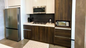 A modern kitchen with stainless steel appliances, wooden cabinets, and a black backsplash.