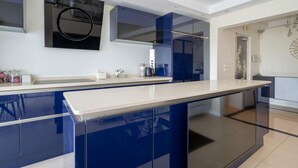 Een moderne keuken met een groot eiland, blauwe kastjes en een wit aanrecht.
