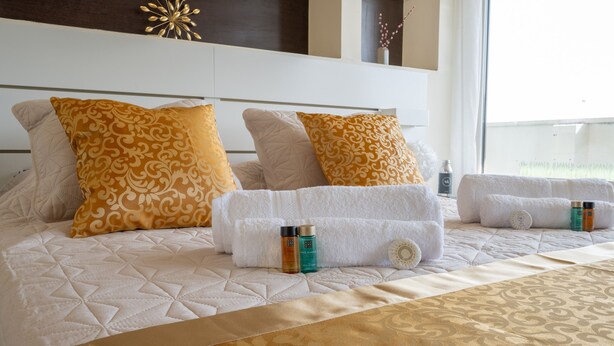 Een hotelkamer met een groot bed, meerdere kussens, een hoofdeinde en een raam met uitzicht.