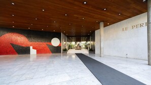 Een modern interieur met een houten plafond, een groot abstract schilderij en een bord waarop 'LE PERI' staat.