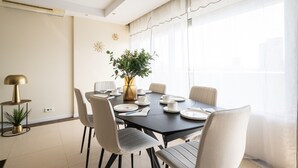 Een eetgedeelte met een ronde tafel, stoelen, een plant en een lamp.