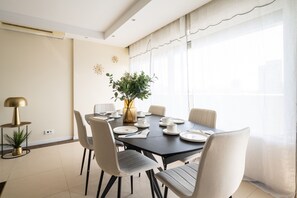 A dining area with a round table, chairs, a plant, and a lamp. - Appartement Skyline Italie - Welkeys (Paris)