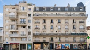 Un edificio de varios pisos con balcones, una farmacia y una señal de estacionamiento.