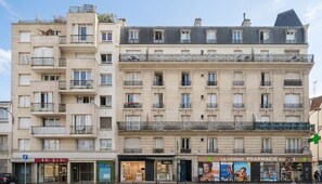 A multi-story building with balconies, a pharmacy, and a parking sign. - Le Charonne Haussmann - Welkeys (Paris)