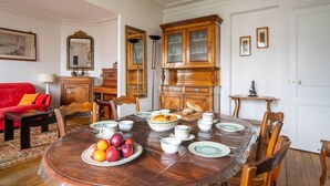 Comedor con una mesa redonda dispuesta para una comida, rodeado de sillas de madera.