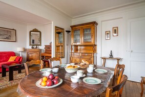 A dining room with a round table set for a meal, surrounded by wooden chairs. - Le Charonne Haussmann - Welkeys (Paris)