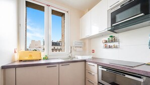 Una cocina moderna con horno integrado, microondas y ventana con vistas a edificios.