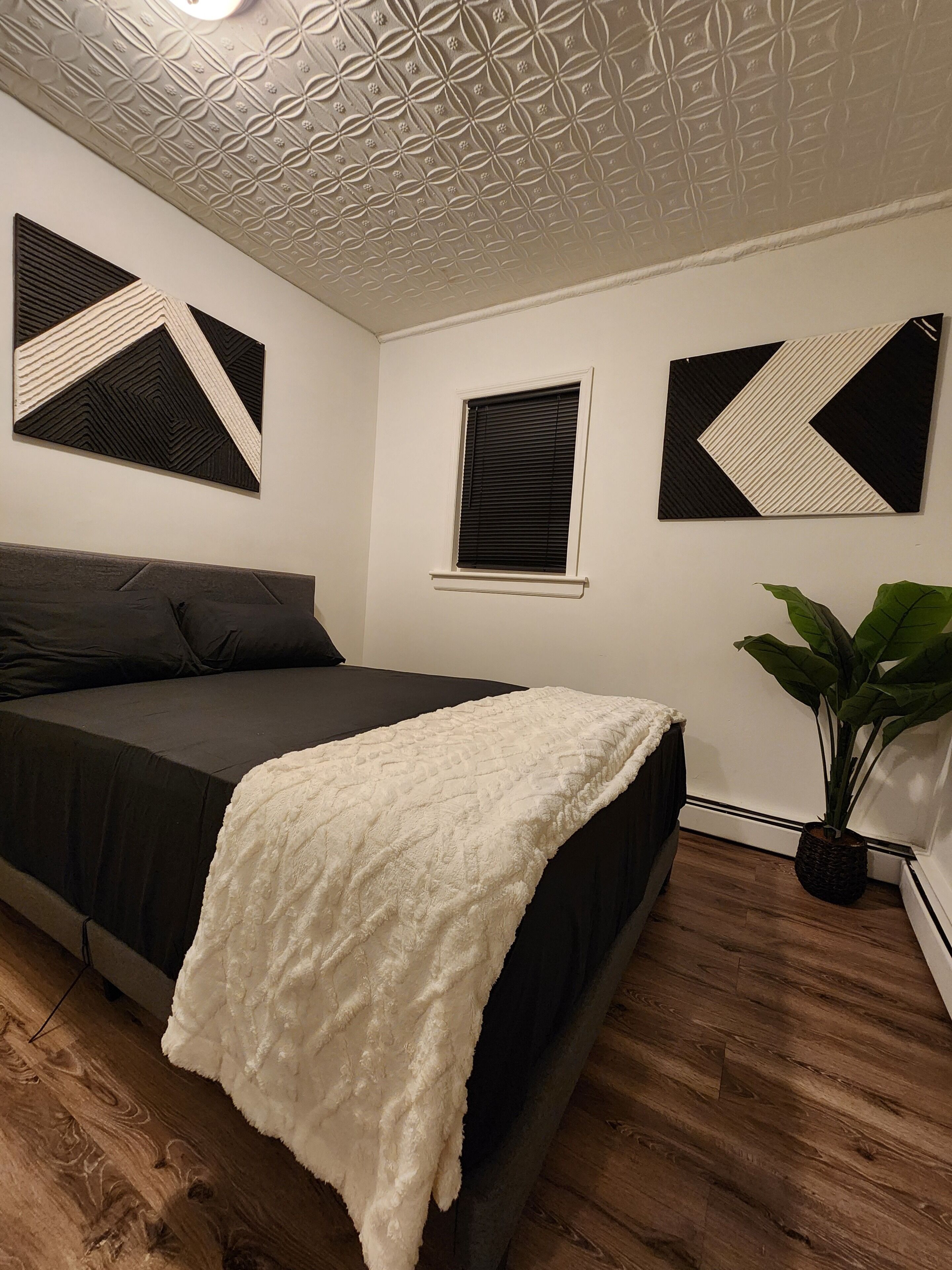 A bedroom with a bed, a window, and a plant.