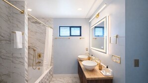 A modern bathroom with a marble shower, two sinks, a large mirror, and a window. - Welcoming 4-bedroom house with AC in Long Beach (Long Beach)
