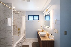 A modern bathroom with a marble shower, two sinks, a large mirror, and a window. - Welcoming 4-bedroom house with AC in Long Beach (Long Beach)