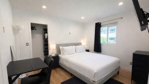A hotel room with a bed, a desk, a chair, a wardrobe, and a TV. - Welcoming 4-bedroom house with AC in Long Beach (Long Beach)
