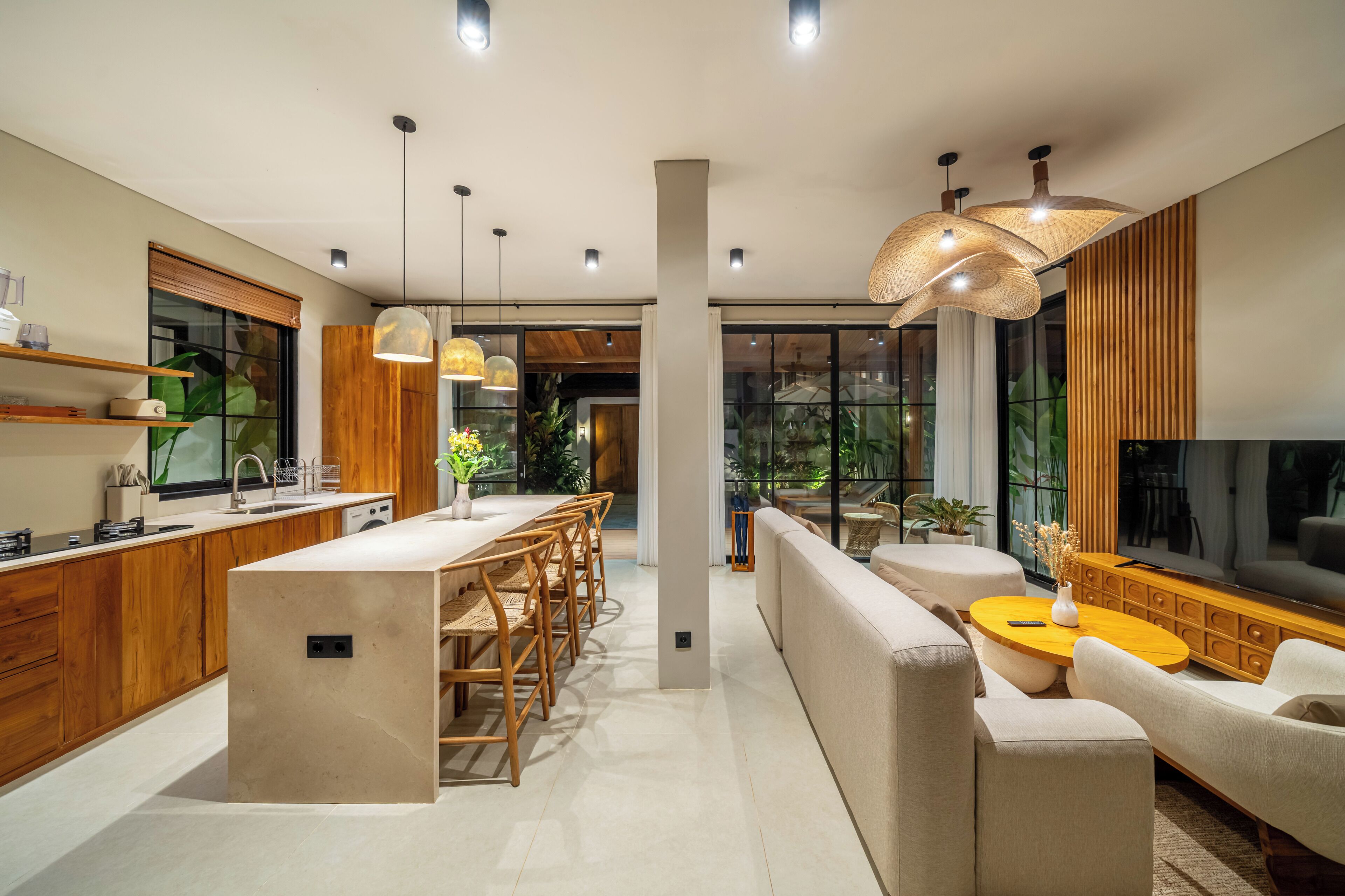 Una cocina moderna con armarios de madera, una isla central y una zona de comedor con sofá y mesa de centro.