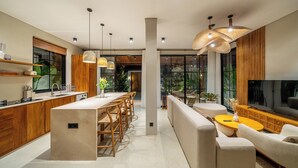 Una cocina moderna con armarios de madera, una isla central y una zona de comedor con sofá y mesa de centro.