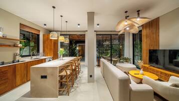 Una cocina moderna con armarios de madera, una isla central y una zona de comedor con sofá y mesa de centro.