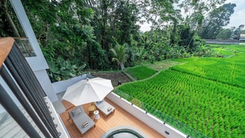 Una terraza moderna al aire libre con piscina, sillones de descanso y vistas a extensos campos de arroz verdes.