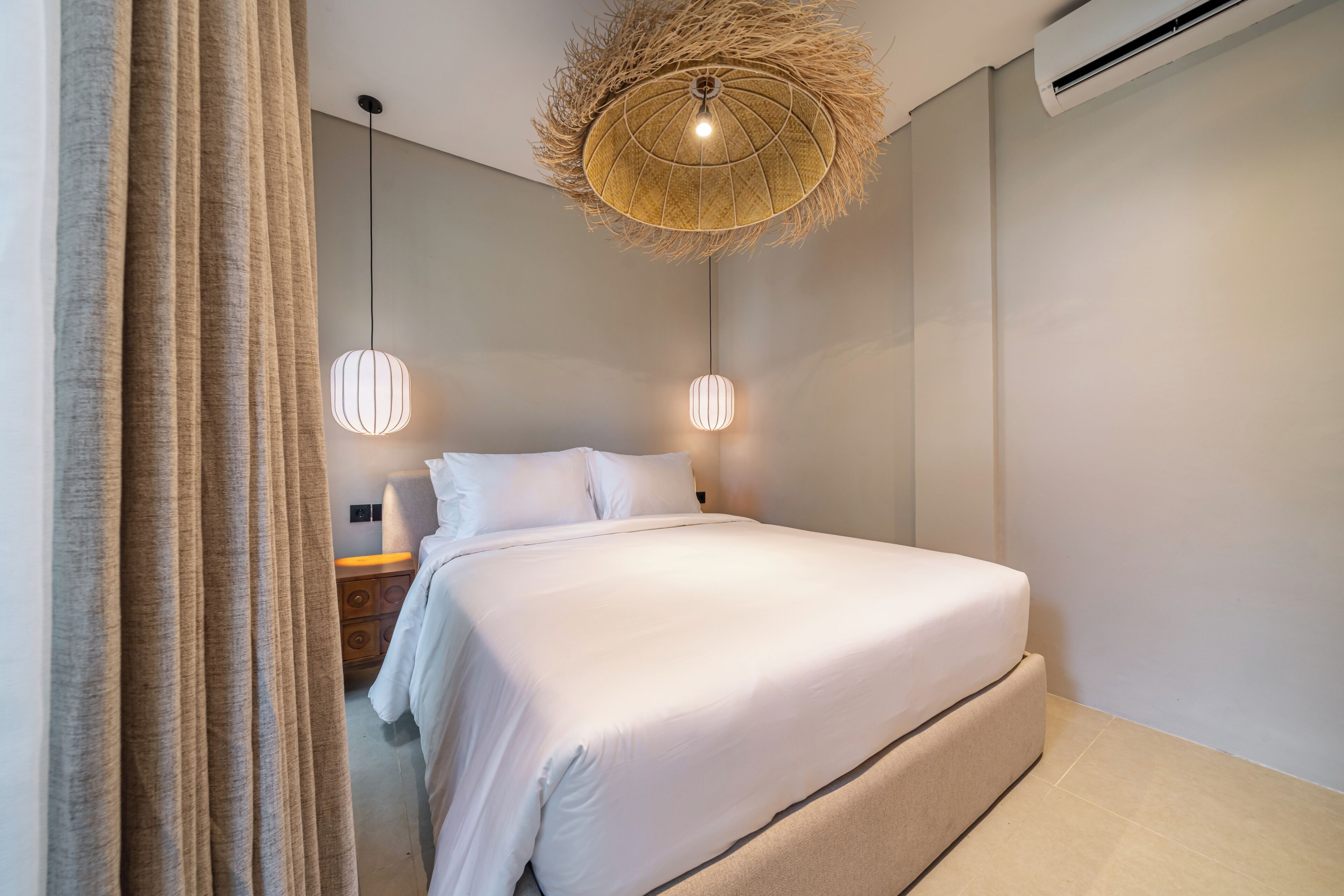 A modern bedroom with a large bed, two bedside lamps, and a unique ceiling light fixture.