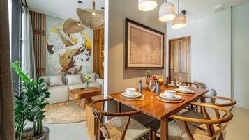 Un comedor con una mesa de madera dispuesta para cuatro personas, rodeada de sillas de mimbre.