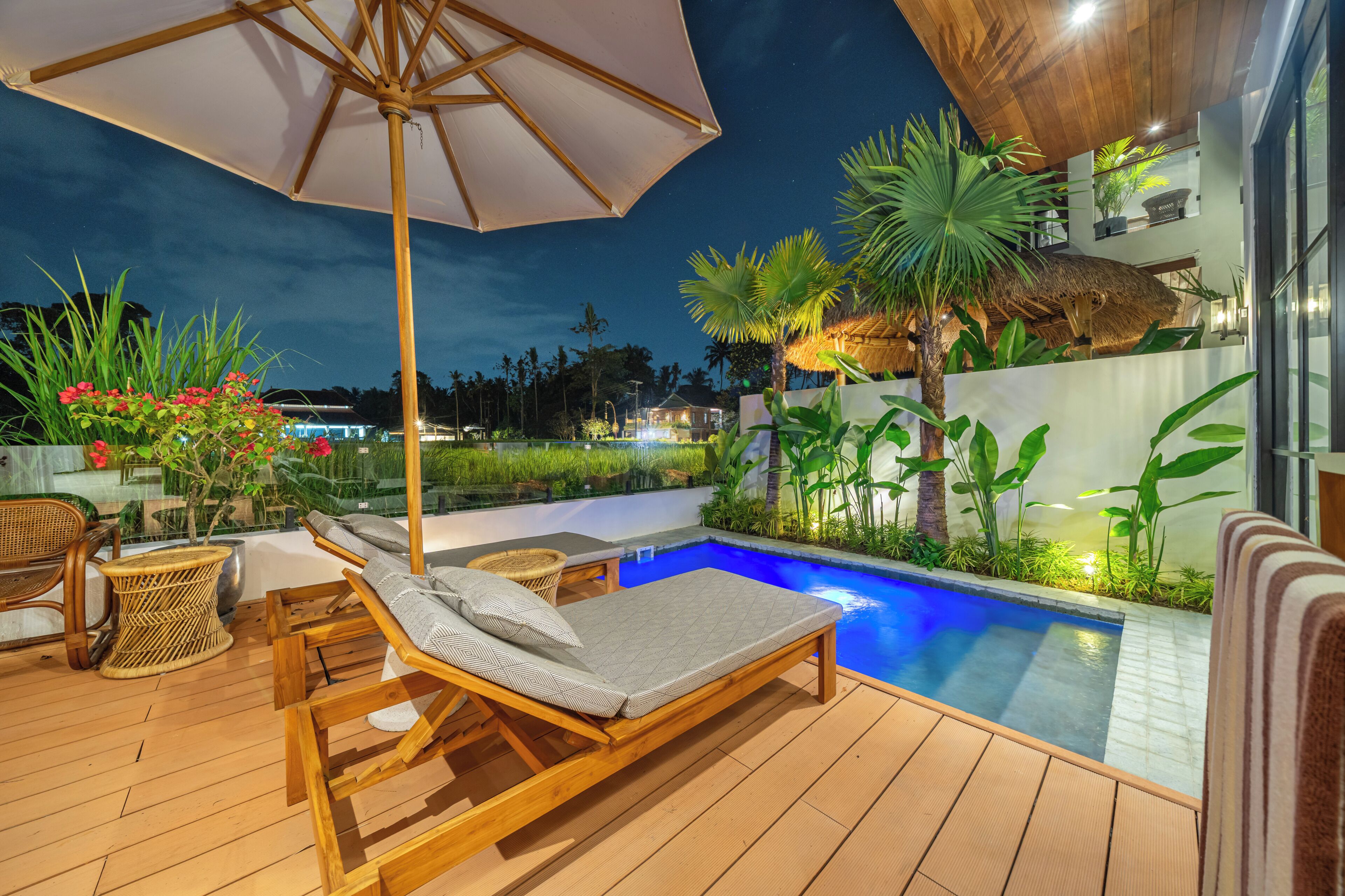 A wooden deck with lounge chairs and a pool area.