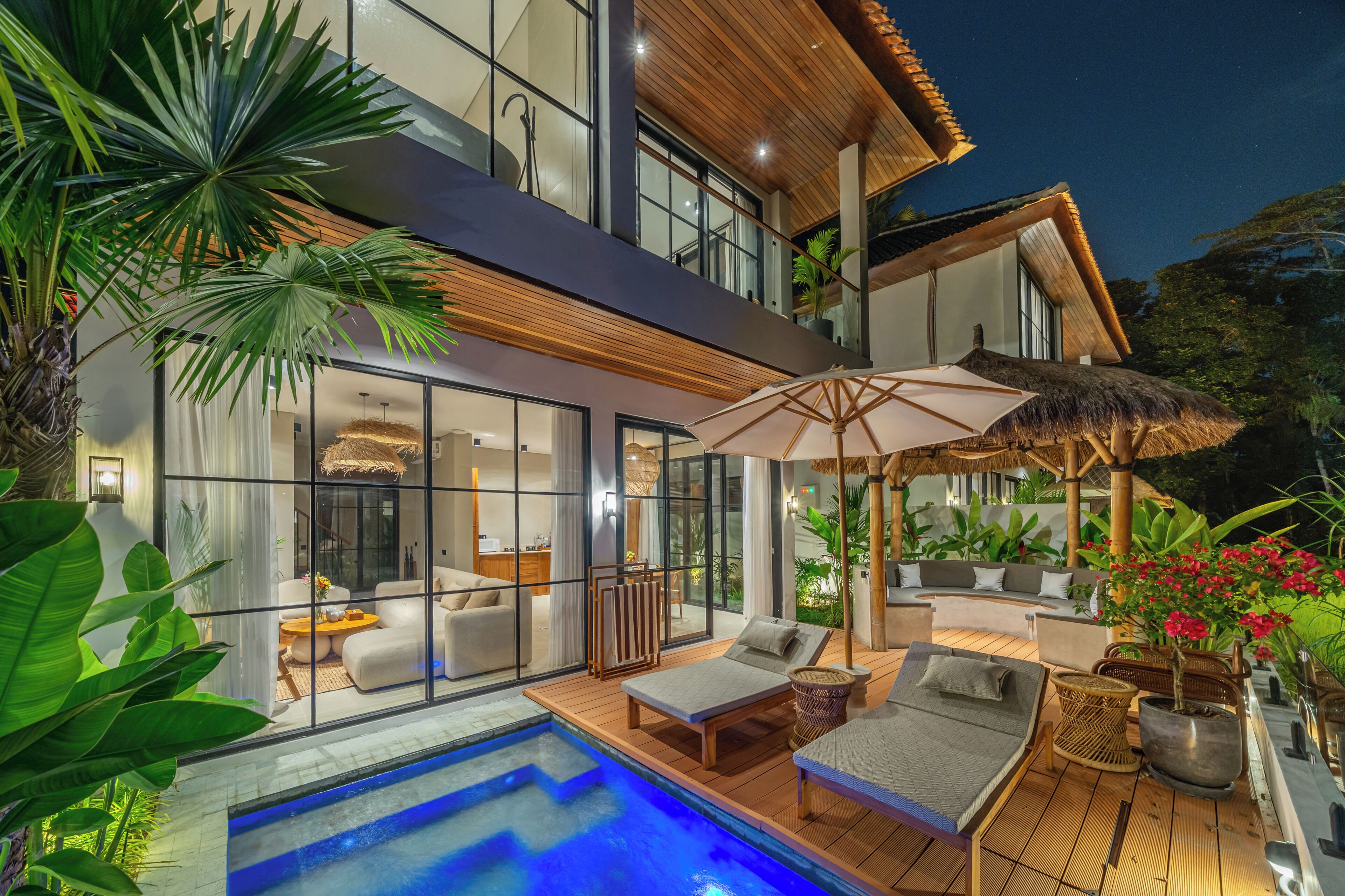 A modern house with a swimming pool, outdoor seating, and lush greenery.