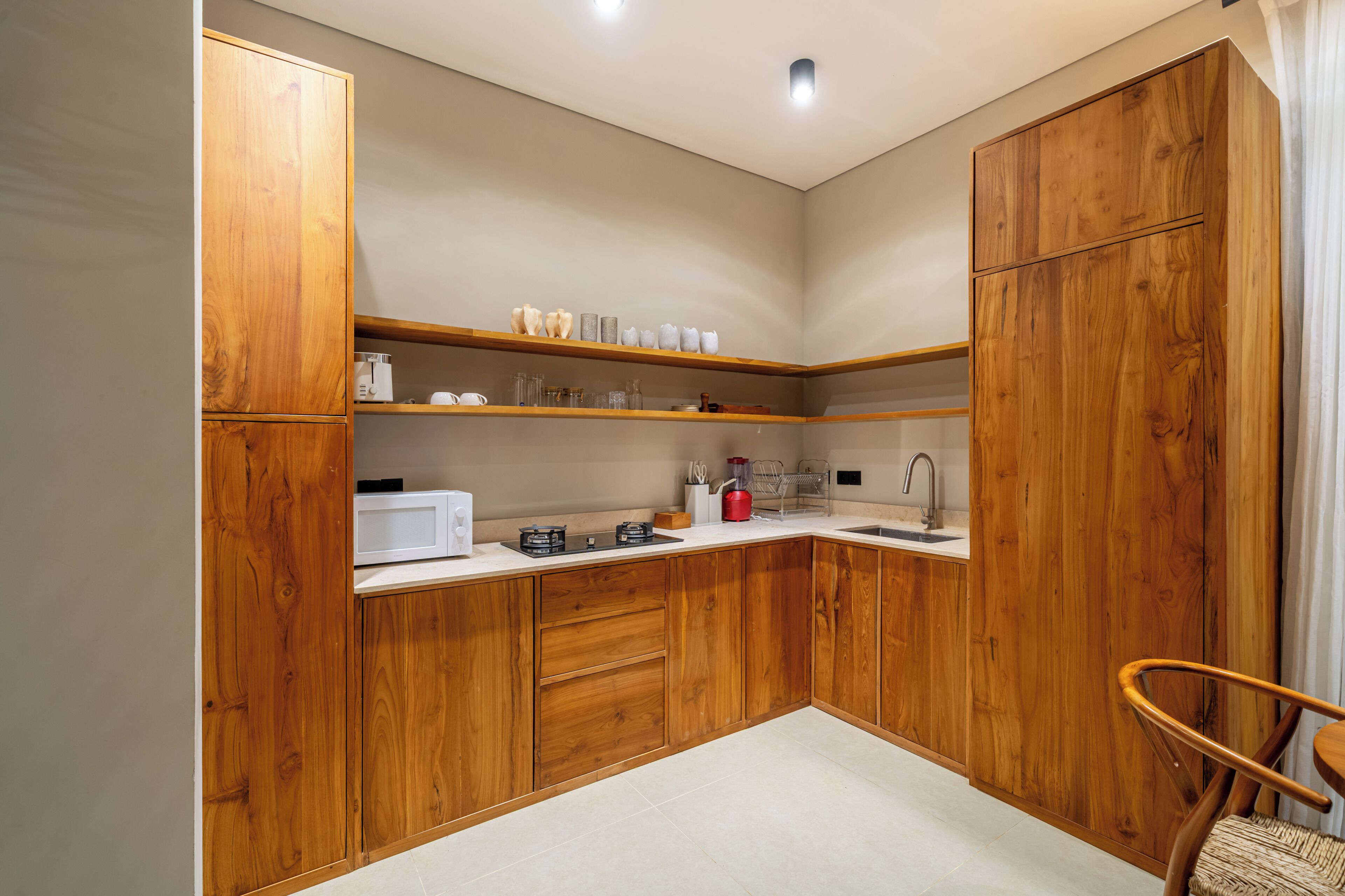 Una cocina compacta con armarios de madera, microondas, estufa a gas y un lavamanos.