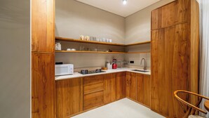 Una cocina compacta con armarios de madera, microondas, estufa a gas y un lavamanos.