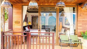 A wooden cabin with a balcony, a bed, a dining table, and two chairs. - Larosa Homestay Sapa (Tả Van)