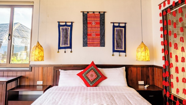 A hotel room with a large bed, wooden ceiling, and a window with a view. - Larosa Homestay Sapa (Tả Van)