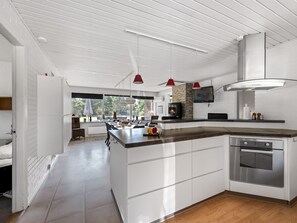 A modern kitchen with a large island, white cabinetry, a built-in oven, and a fireplace. - "Gyrth" - 2.8km from the sea by Interhome (Blåvand)