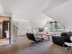 A modern interior with a sloped ceiling, a television, a sofa, and a dining area. - "Gyrth" - 2.8km from the sea by Interhome (Blåvand)