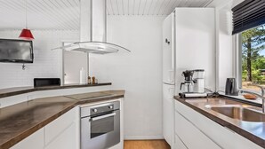 Eine moderne Küche mit Backofen, Kaffeemaschine und einem Fenster mit Blick ins Grüne.