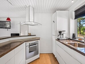 Eine moderne Küche mit Backofen, Kaffeemaschine und einem Fenster mit Blick ins Grüne.