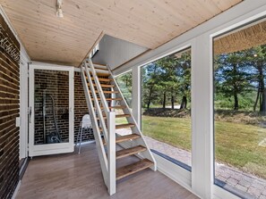 A modern interior with a wooden staircase leading to a glass door, a brick wall, and a view of a grassy area. - "Gyrth" - 2.8km from the sea by Interhome (Blåvand)