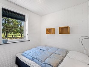 A bedroom with a bed, a window with blinds, a bedside lamp, and two wall-mounted baskets. - "Gyrth" - 2.8km from the sea by Interhome (Blåvand)
