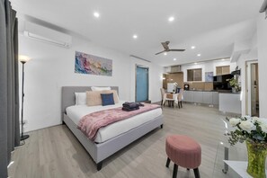 Een moderne slaapkamer met een bed, nachtkastje en een zithoekje.