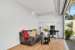 A modern living room with a leather sofa, a small table, and a black office chair. - 11+ Guests | 6BR (5+1 Self Contained Granny Flat) (Athelstone)