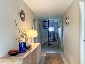Ein Flur mit einem Holzkonsolentisch, einer Lampe, einer Schale und einer Wendeltreppe.