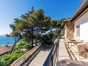 A balcony with a stone wall, wooden furniture, and a view of the sea. - A Casa di amici by Interhome (Marina di Andora)