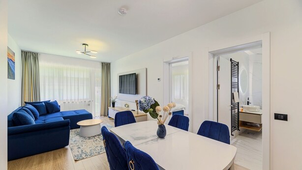 Een moderne woonkamer met een bank, een eettafel en een televisie.
