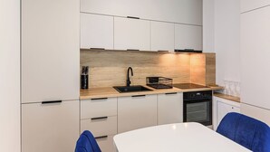 Een moderne keuken met witte kastjes, een houten aanrechtblad, een zwarte spoelbak en een inbouwoven.