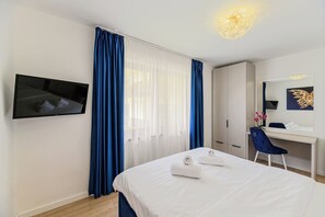 A hotel room with a bed, a desk, a chair, a TV, and a large window with curtains. - Art by Grand Chalet (Brașov)