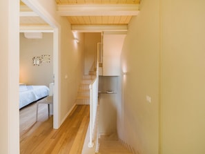 Ein schmaler Gang mit einer Treppe, die zu einem Schlafzimmer führt.