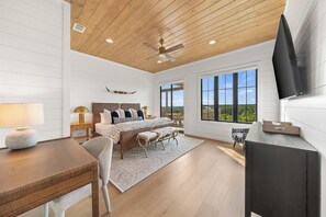 Une chambre spacieuse avec un grand lit, un bureau et un téléviseur fixé au mur.