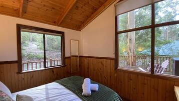 A wooden-paneled room with a bed, large windows, and a view of the outdoors.