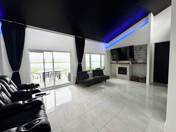 Uma sala de estar moderna com um sofá, poltronas, uma televisão de tela plana e uma lareira.