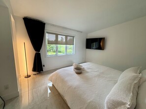 Quarto com cama, janela, televisão de tela plana e abajur.