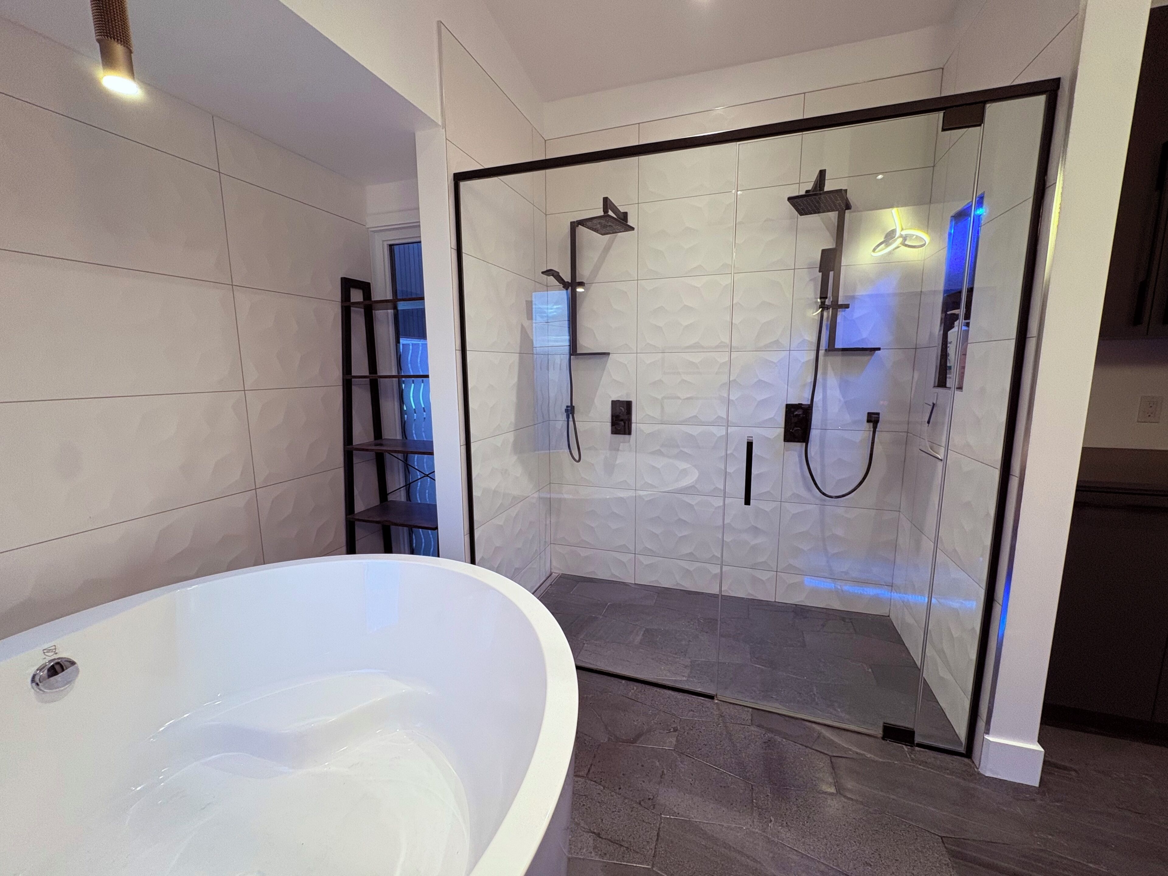 Une salle de bain moderne avec une baignoire sur pieds, une douche à l’italienne et une étagère intégrée.