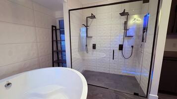 Une salle de bain moderne avec une baignoire sur pieds, une douche à l’italienne et une étagère intégrée.