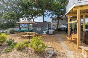A backyard with a picnic table, barbecue grill, and a swing set. - Villa Delfino - 4 BR 3 Bth dog-friendly, bay home with pool and dock (Virginia Beach)